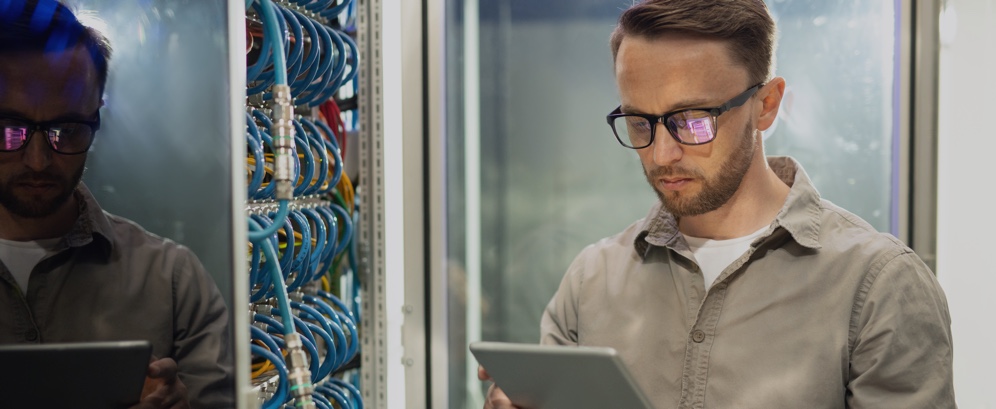 Man with Glasses Looking at Tablet Next to Structured Cabling Wires – Data Line Technologies