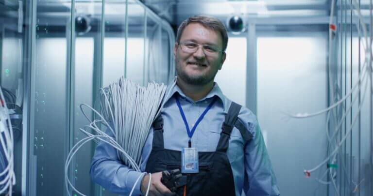 Cabling technician smiling carrying cables after a site survey for installation in a server room